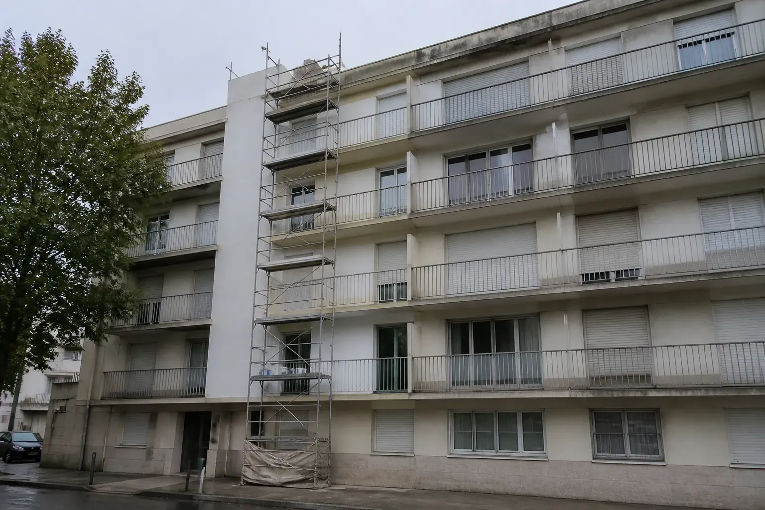 Façade d’immeuble collectif des années 1960 et 1970 en cours de ravalement, balcons filants et échafaudage monté sur une travée